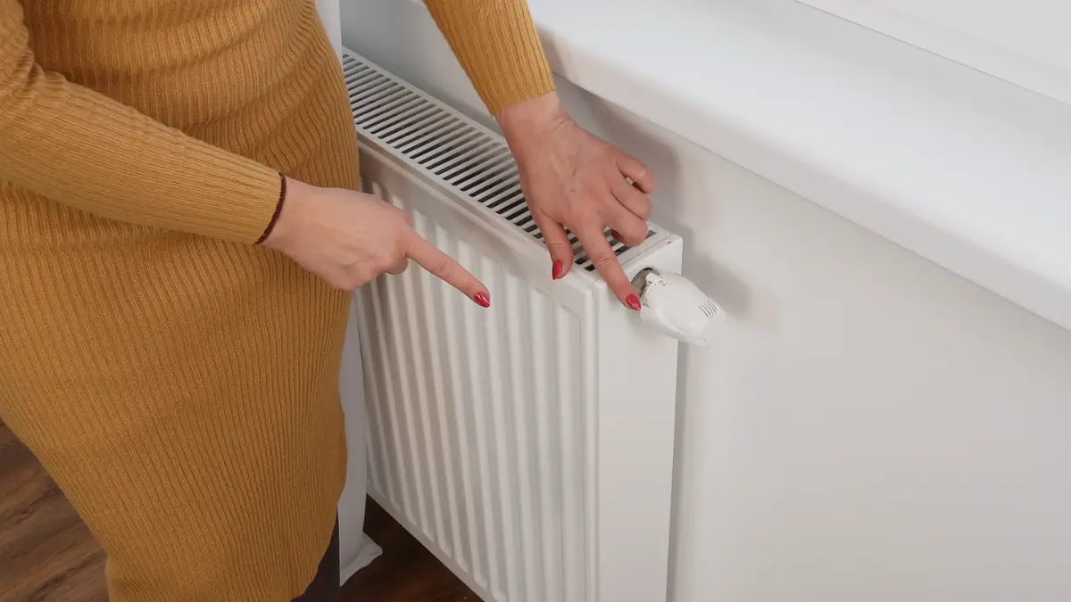 Dłonie sprawdzające temperaturę rozgrzewającego się grzejnika
