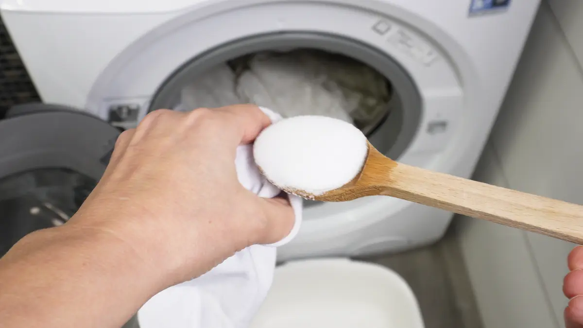 Wlewanie jasnego octu z plastikowej butelki do dozownika na płyn do płukania w pralce