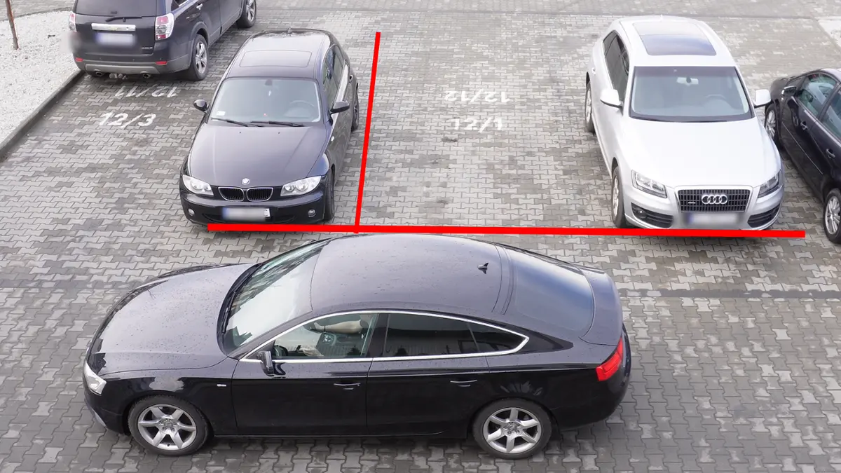 Widok z góry na samochód parkujący tyłem między liniami na placu parkingowym