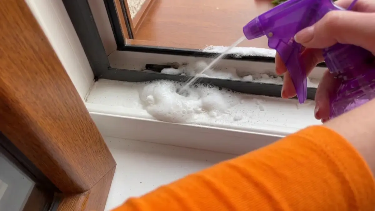 Aplikacja domowej mieszanki z octu i sody na zabrudzoną ramę okienną