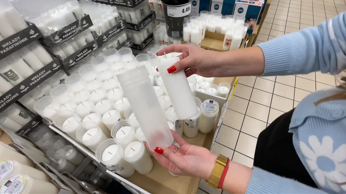 Kobieta porównująca w obu dłoniach dwa różne wkłady do zniczy w marketach